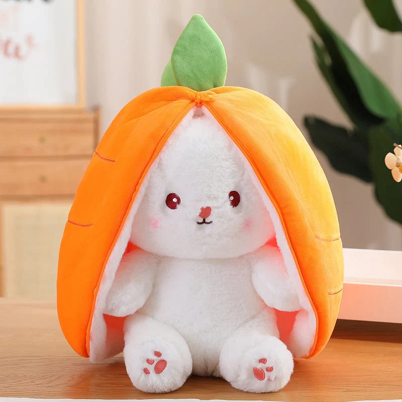 Plush toy resembling a white rabbit with orange shell and green leaf on a wooden surface.