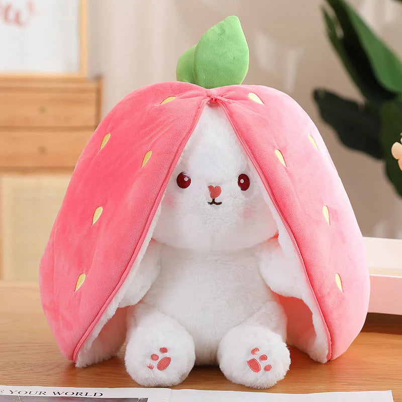 Plush toy shaped like a strawberry with a white rabbit inside on a wooden surface.