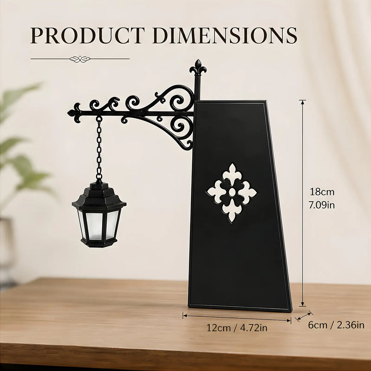 Black decorative wall-mounted lantern with ornate scrollwork and a hanging lantern shade, shown on a tabletop with overlaid product dimension labels: 18 cm height, 12 cm width, and 6 cm depth.