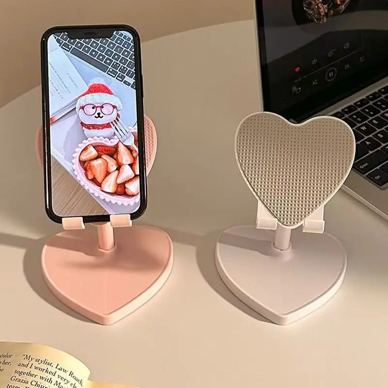 Heart-shaped phone stands on a desk with a phone displaying a dessert image.