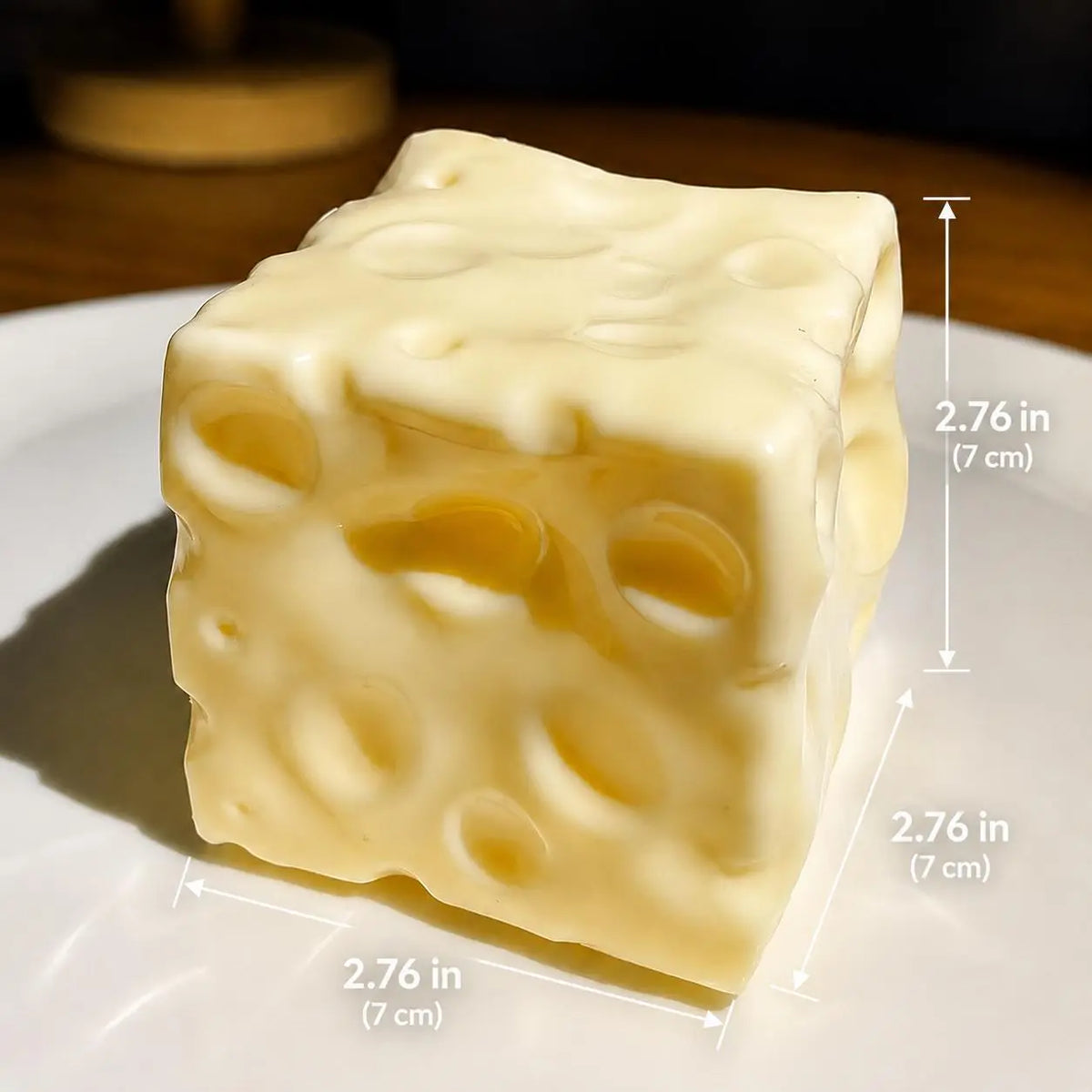 A Moldable Cheese Squishyon a white plate, with dimension lines and text showing measurements of 2.76 in (7 cm) on each side.