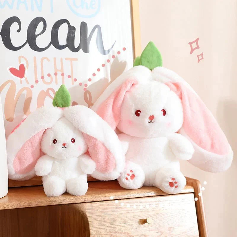 Two plush toys resembling bunnies with green leaves on a wooden surface.