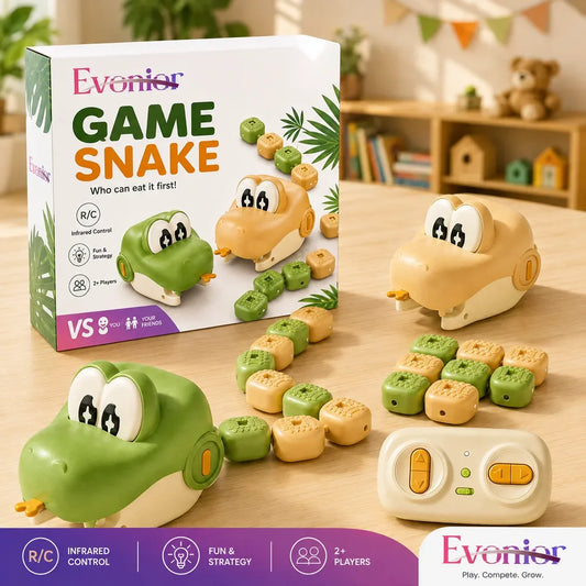 Evenior Game Snake toy set on a wooden table, showing the retail box, a green frog-shaped player, a beige snake-shaped player, several green and beige food pieces, and a white remote control. The background is a softly blurred children's room with shelves and toys.